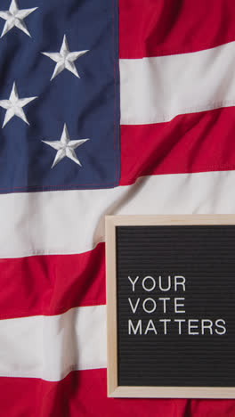 Vertical-Video-Of-Sign-Reading-Your-Vote-Matters-Lying-On-US-Stars-And-Stripes-Flag-For-American-Election-2024